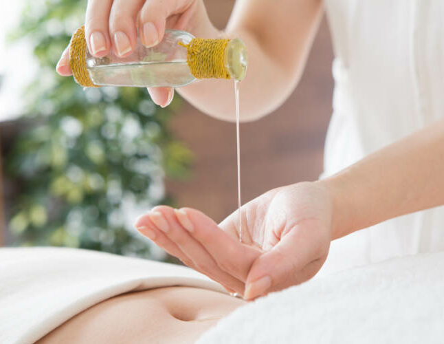 Fließendes Öl in die Hand der Therapeutin für die therapeutische Frauenmassage